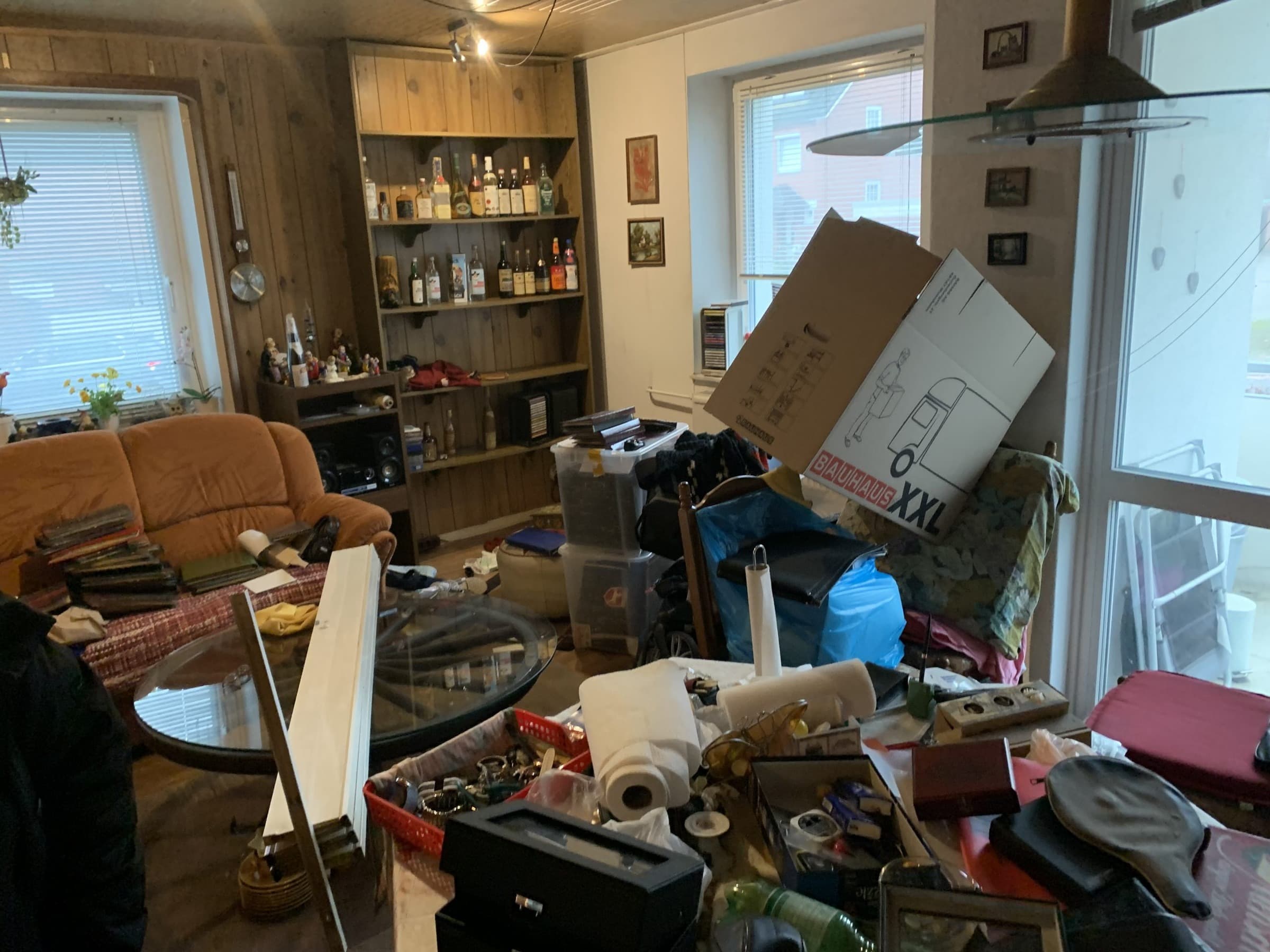 Wohnzimmer vor der Räumung: Kartons, Kisten und Hausrat auf Tisch und Boden