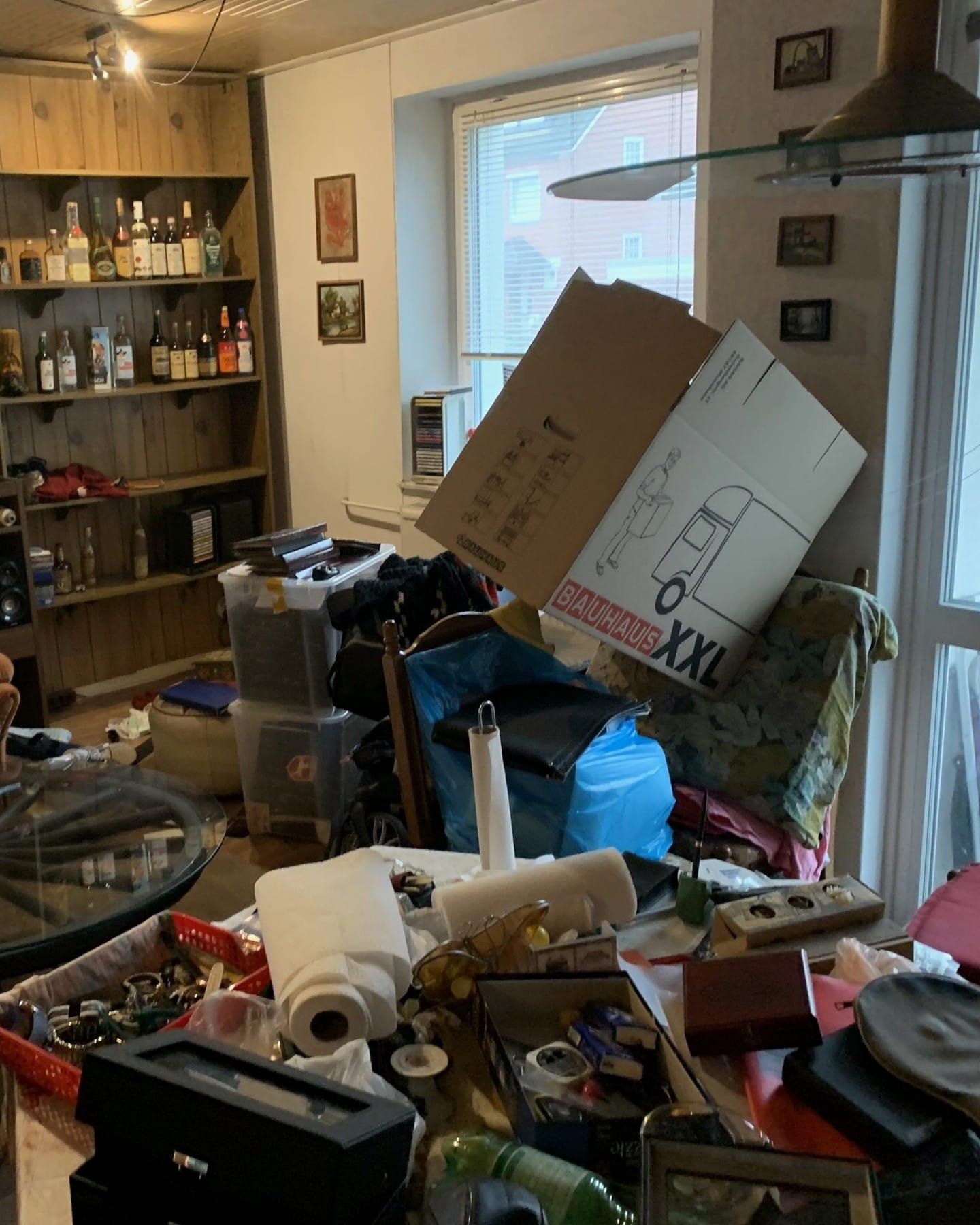 Wohnzimmer vor der Räumung: Kartons, Kisten und Hausrat auf Tisch und Boden