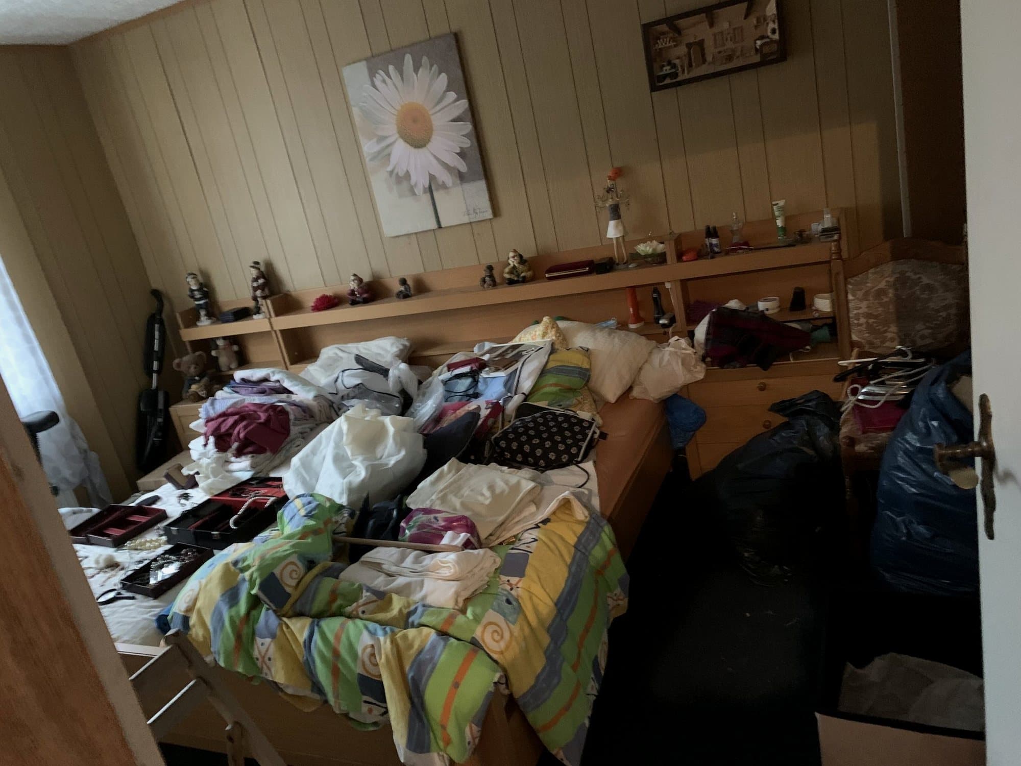 Schlafzimmer vor der Räumung: Bett voller Kleidung und Taschen
