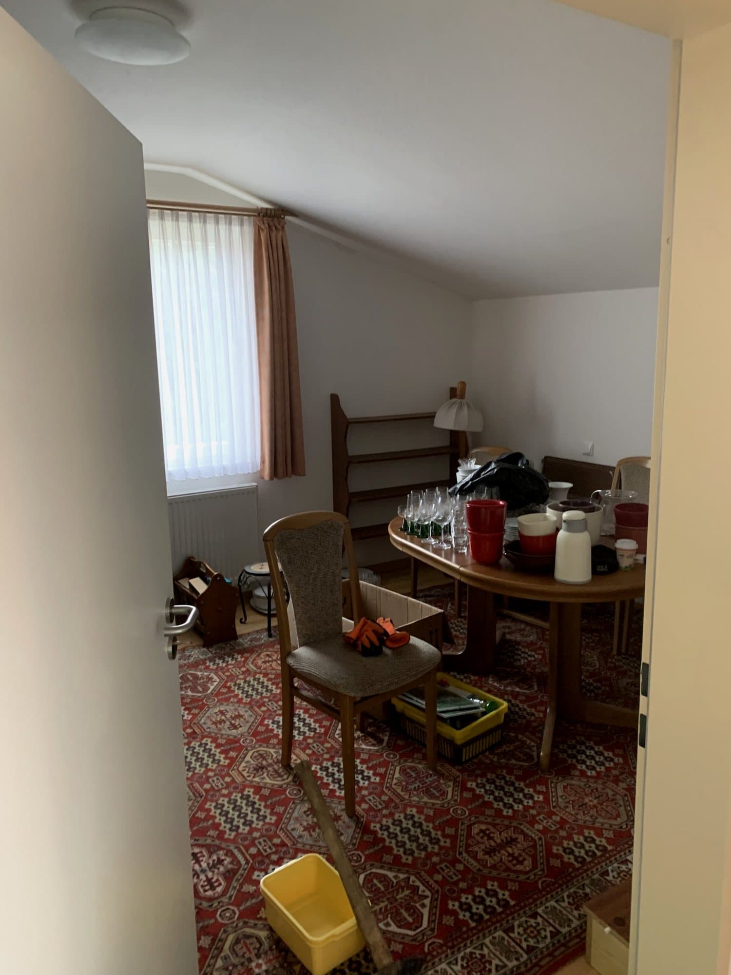 Dachzimmer vor der Räumung mit Tisch, Stühlen und Regal