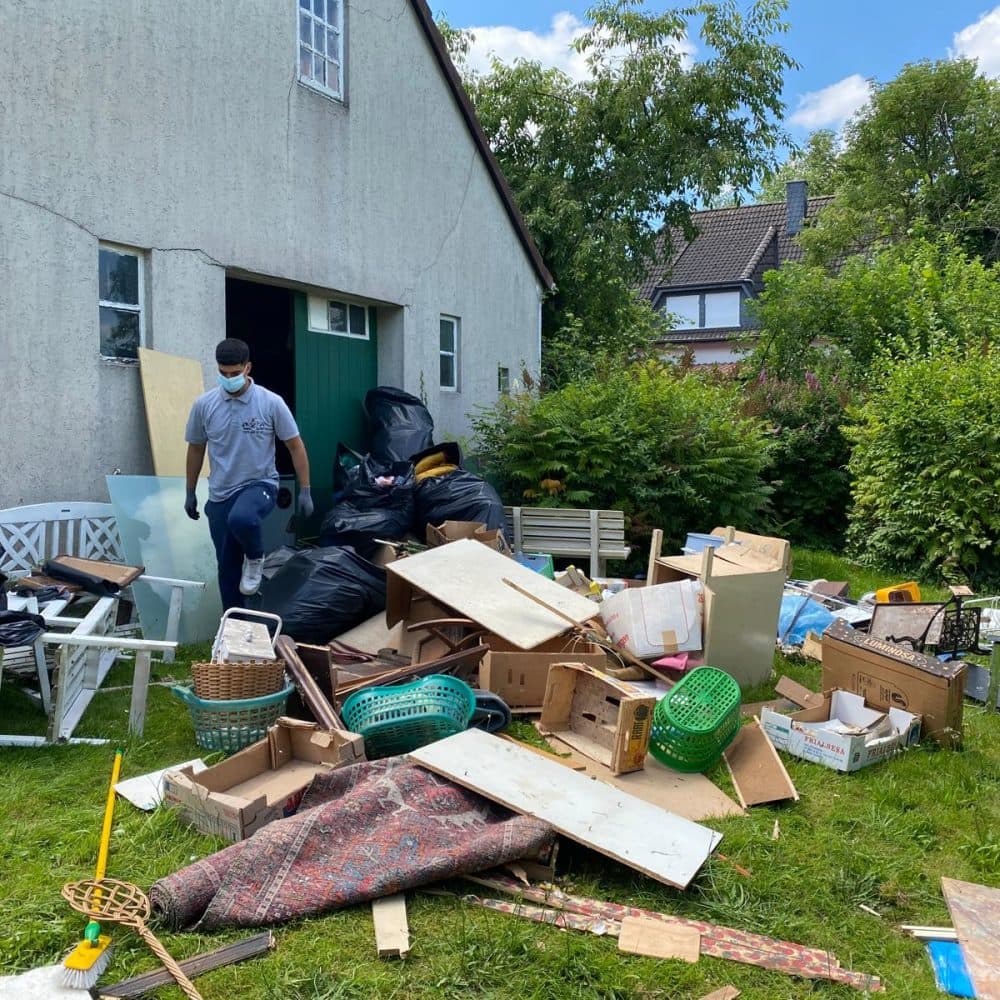 Mitarbeiter trägt Hausrat aus einem Haus in den Garten