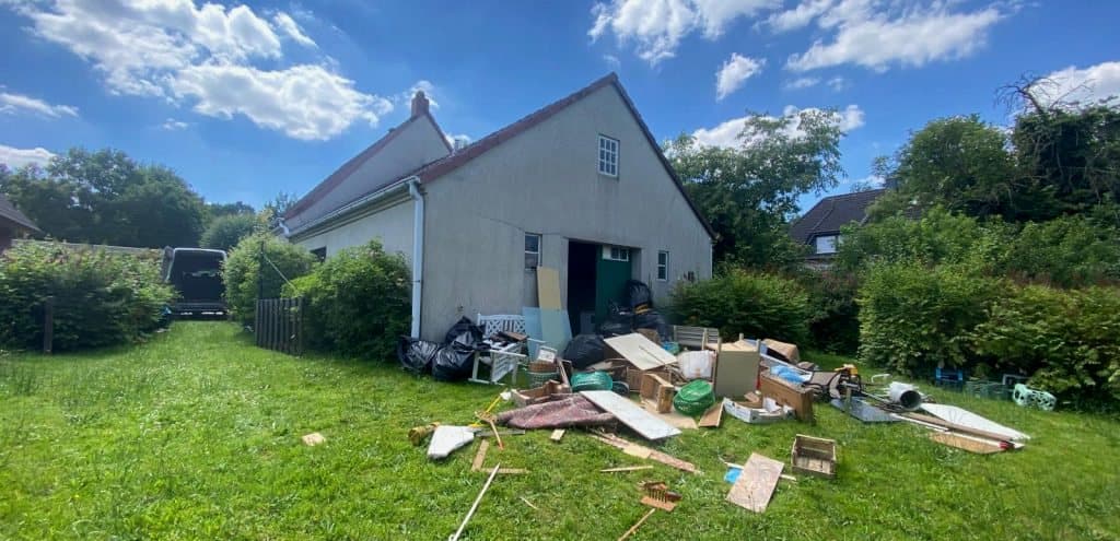 Garten vor einem Haus mit ausgeräumtem Hausrat
