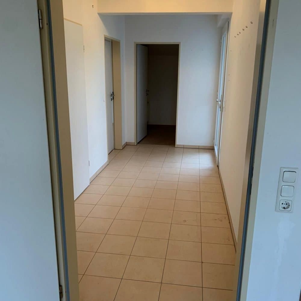 Leerer Flur mit Fliesenboden und offenen Türen